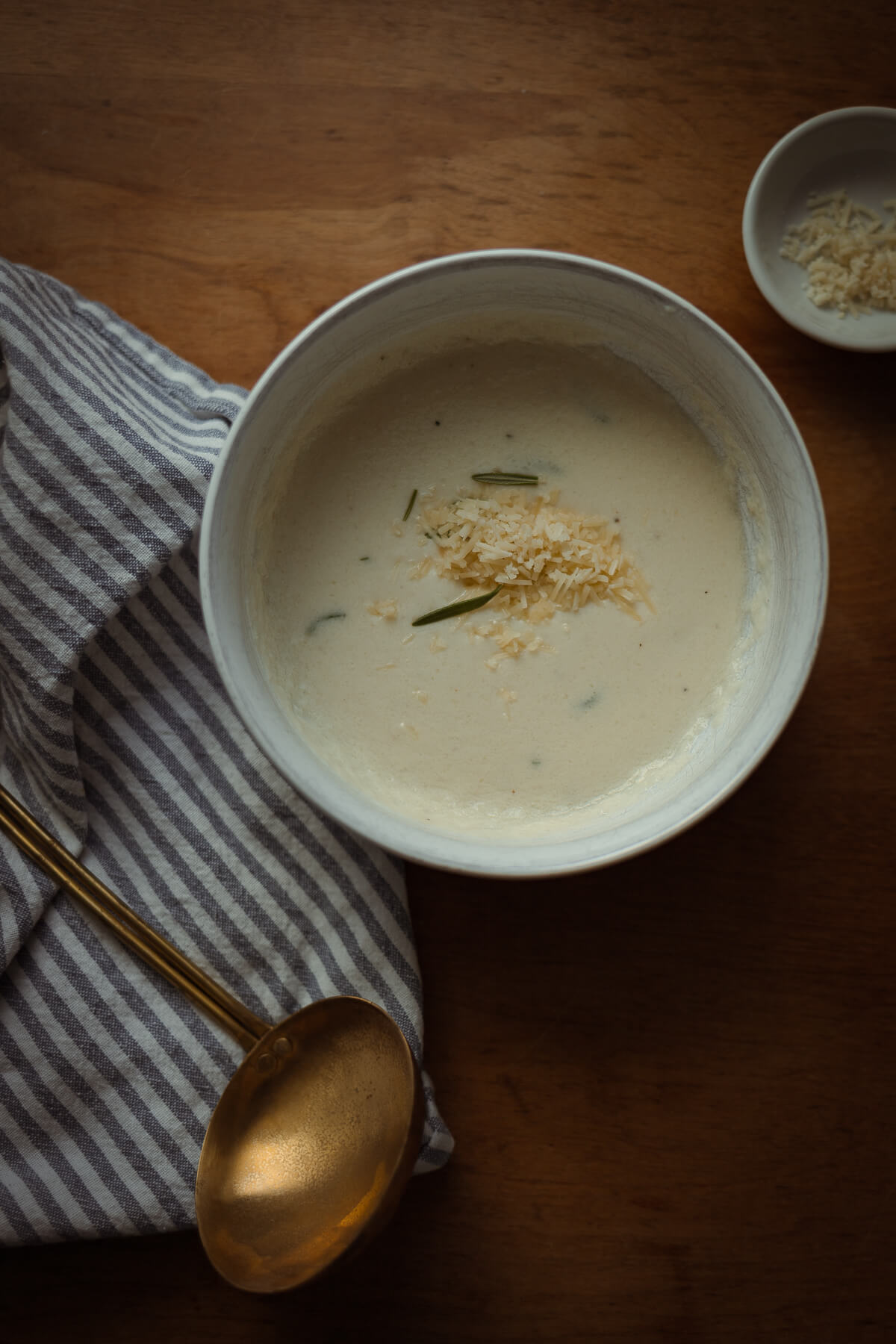 bowl of gluten free cauliflower soup with a ladle sitting nearby