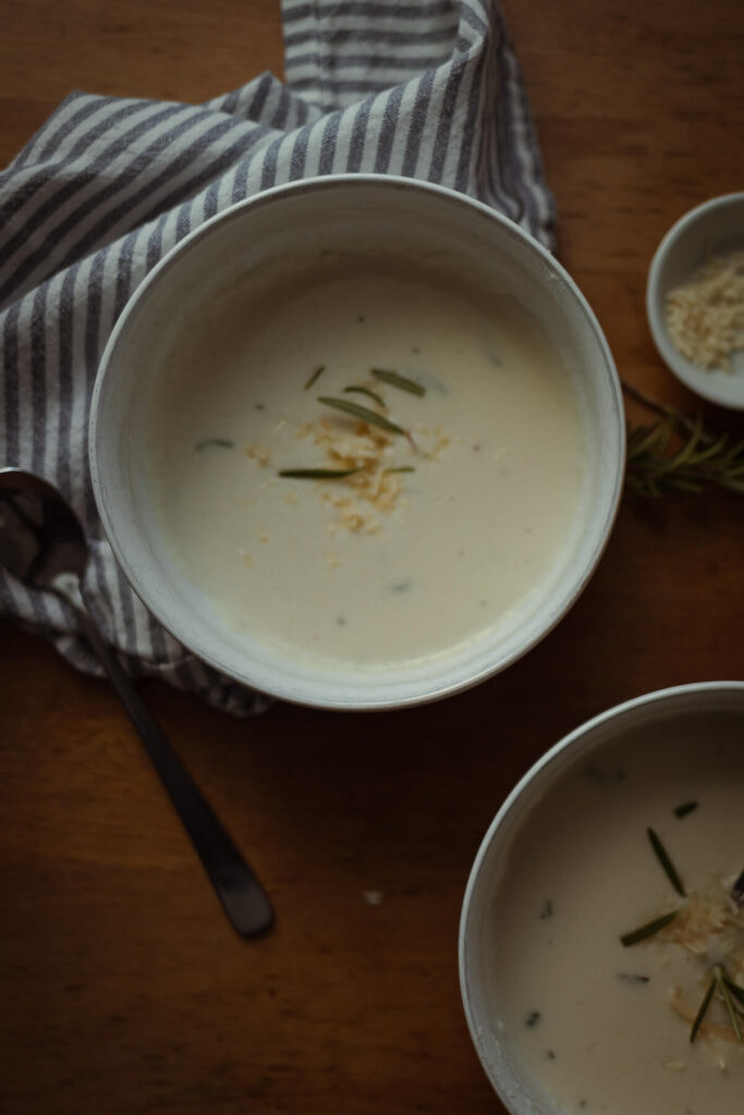 bowl of gluten free cauliflower soup with a spoon sitting nearby