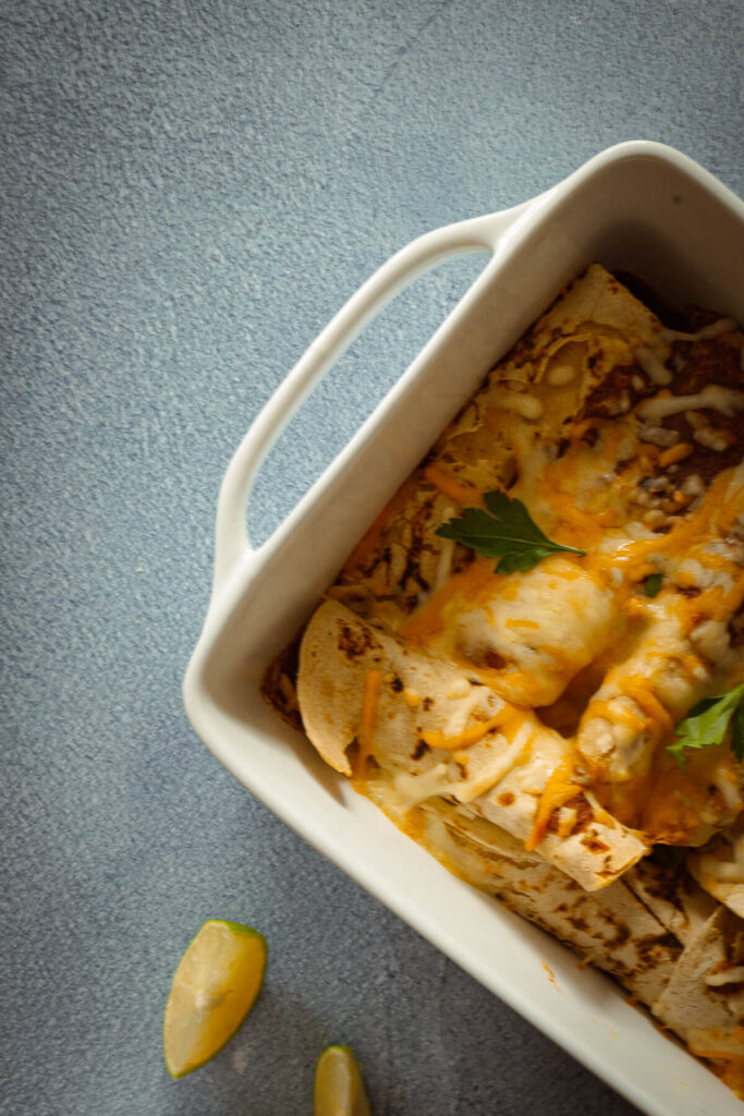 close up of enchiladas in a 9x13 baking pan with melted cheese on top