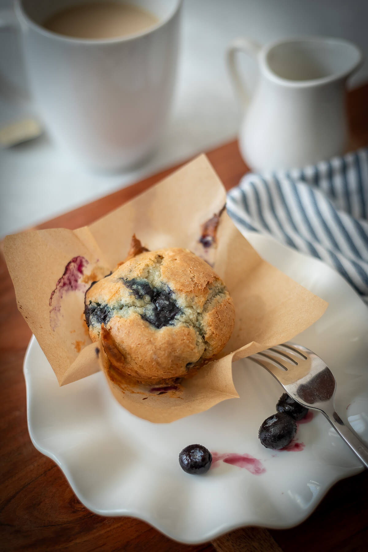 a gluten free blueberry muffin on a plate with a napkin and tea