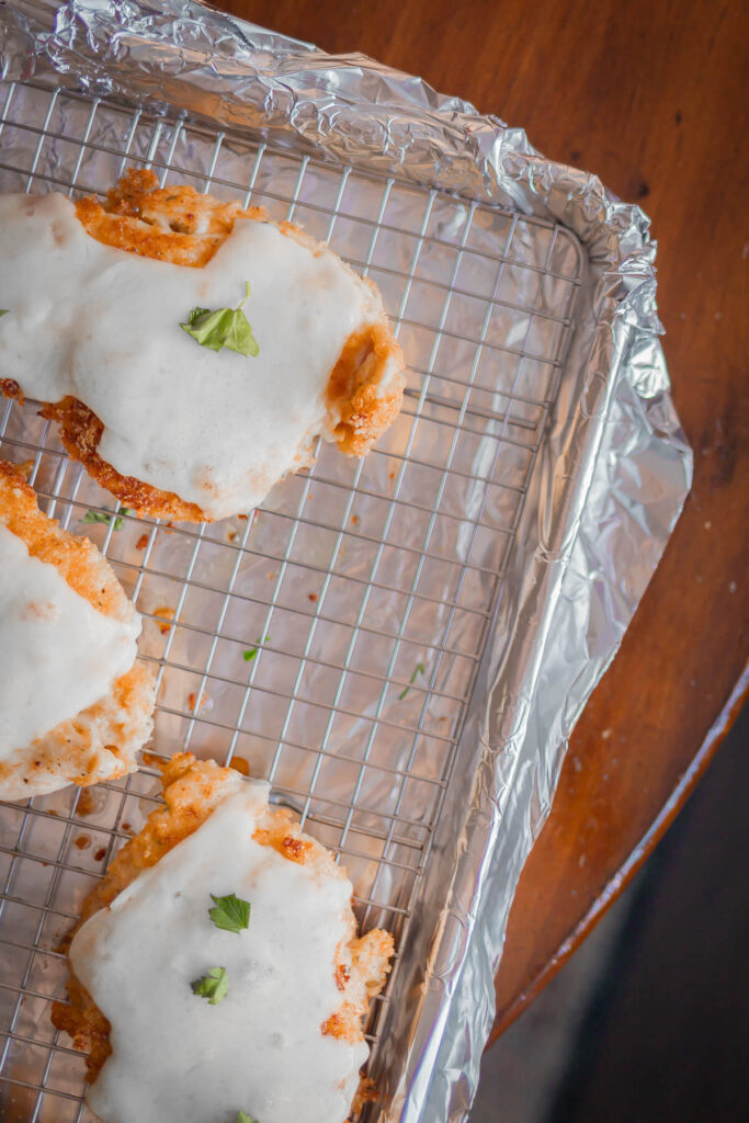 top down view of gluten free breaded chicken with cheese and parsley on top