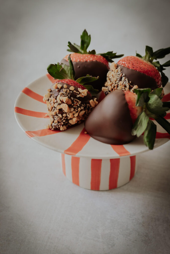 close up view of chocolate covered strawberries with nut toppings - get the recipe inside!