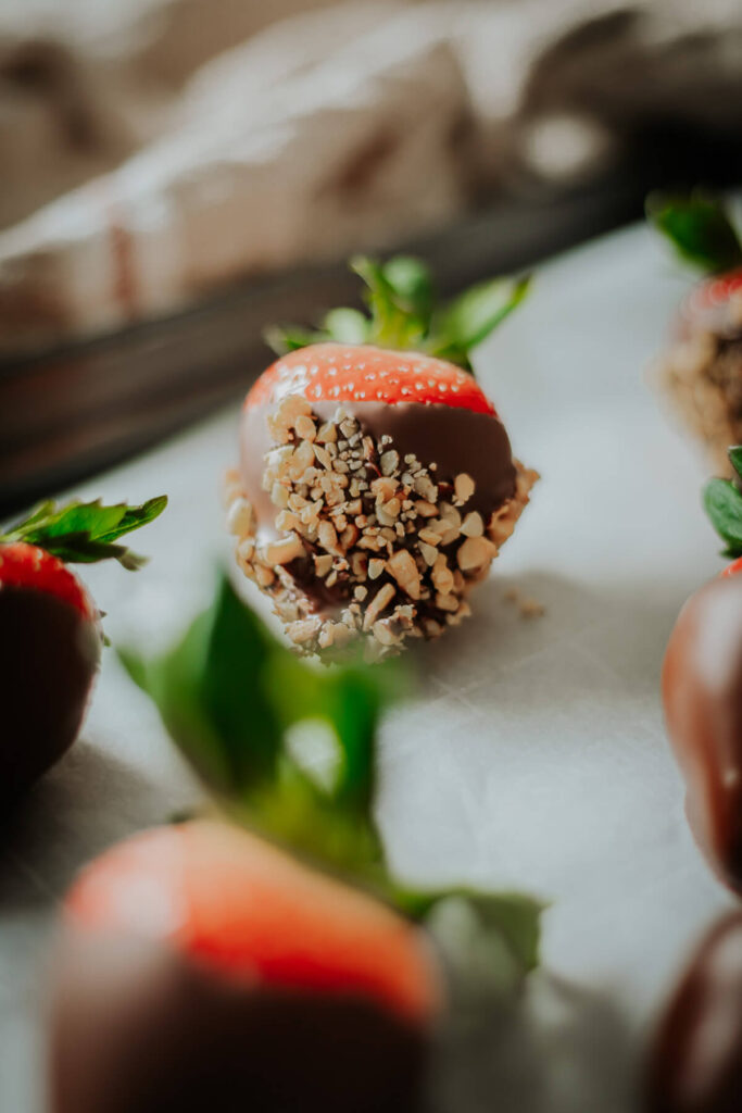 close up view of chocolate covered strawberries with nut toppings - get the recipe inside!