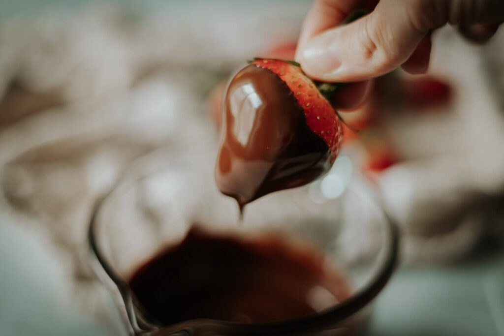 dipping a strawberry into chocolate