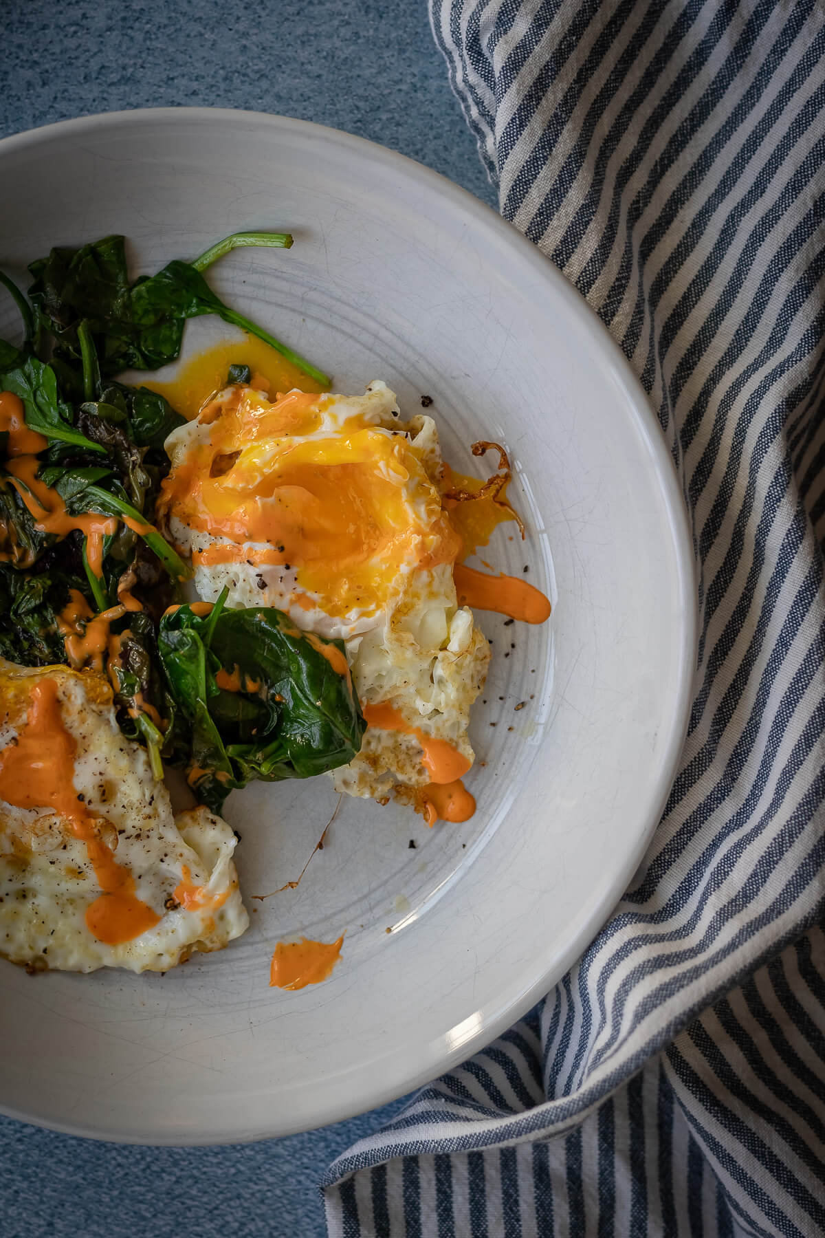 Fried Eggs with sauteed greens and sriracha mayo