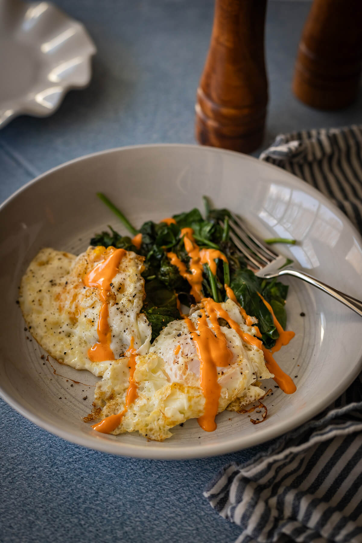 Fried Eggs with sauteed greens and sriracha mayo